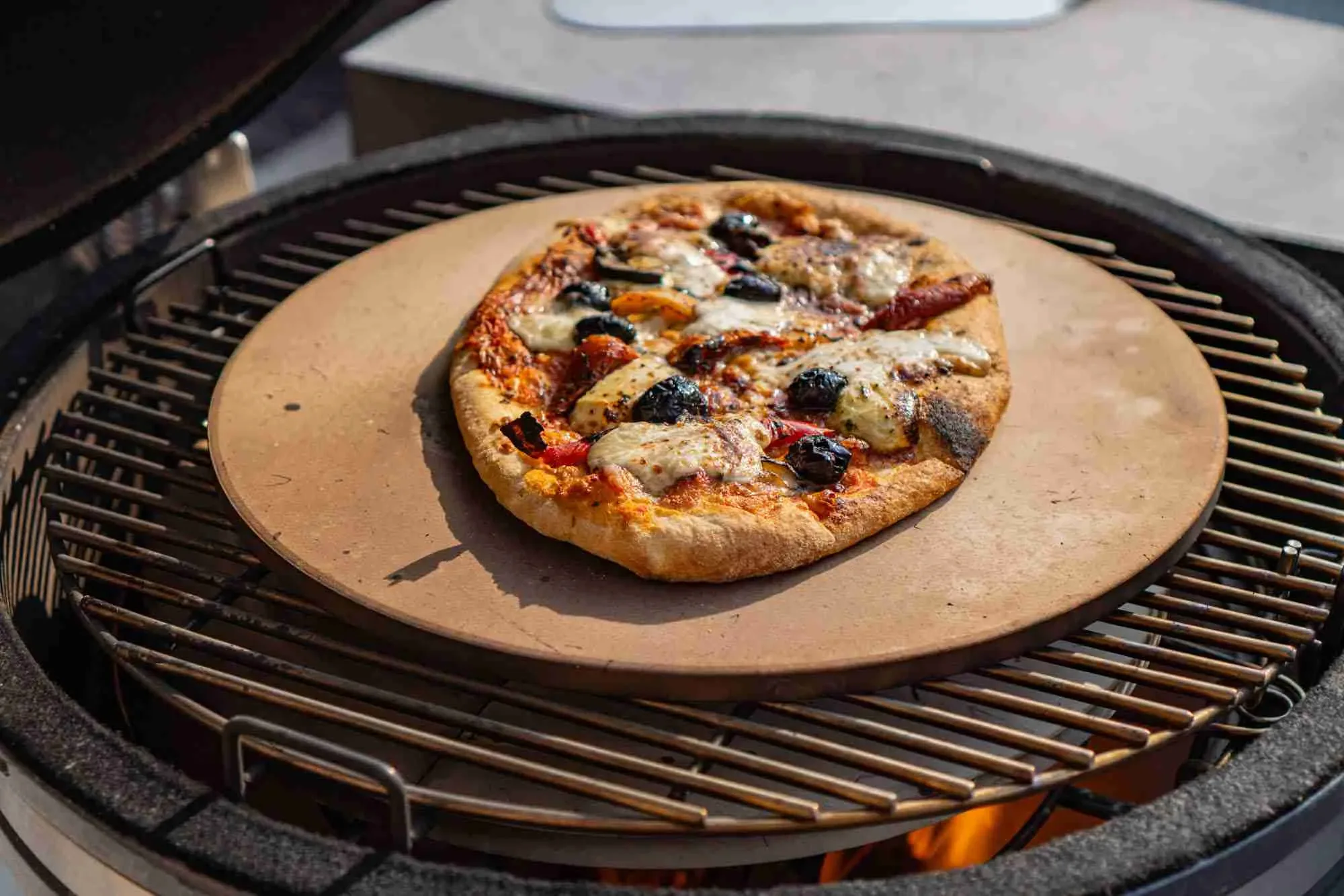 pizza cooking on pizza stone on gusto charcoal bbq