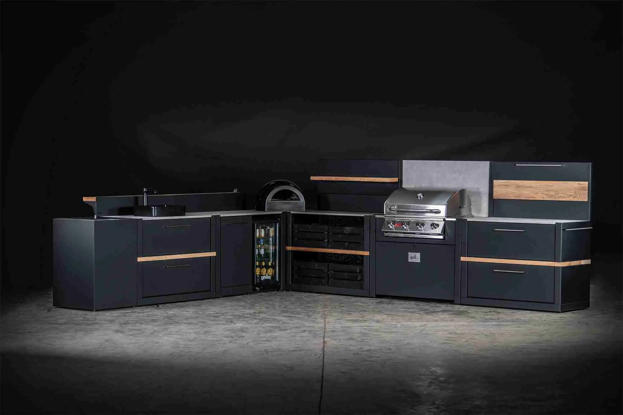 Outdoor kitchen in a studio with pizza oven, gas bbq grill station, storage cabinets and fridge and bin cabinet