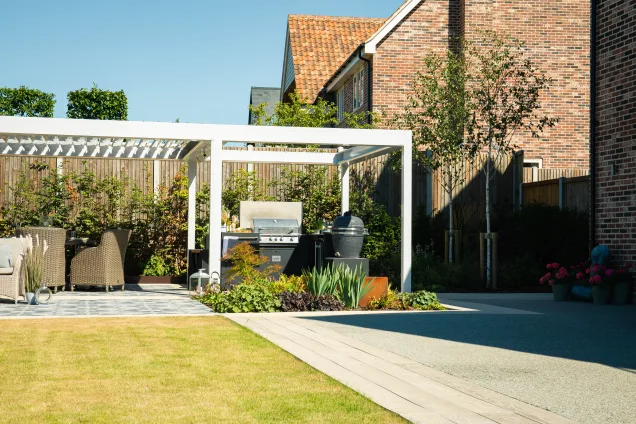 Grillo outdoor kitchen in ardleigh colchester surrounded shrubs and next to a dining area