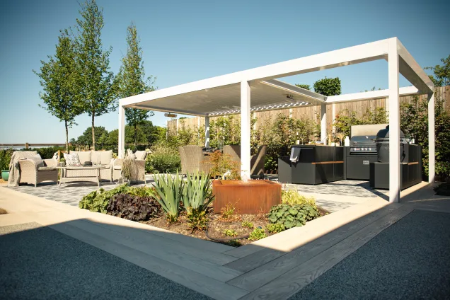 Grillo outdoor kitchen in ardleigh colchester under pergola with shrubs and outdoor seating area