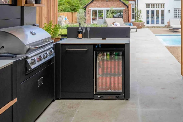 outdoor kitchen on large patio with pool in background