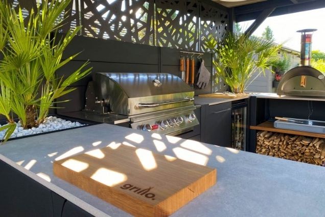 outdoor kitchen with bull gas grill, storage cabinets and a chopping board on the cabinets