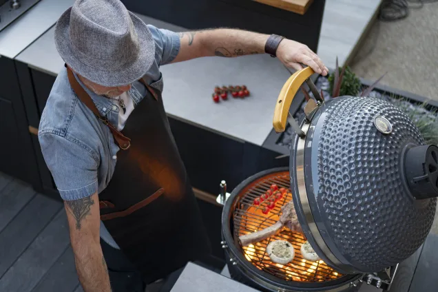 person using gusto charcoal bbq to cook steak