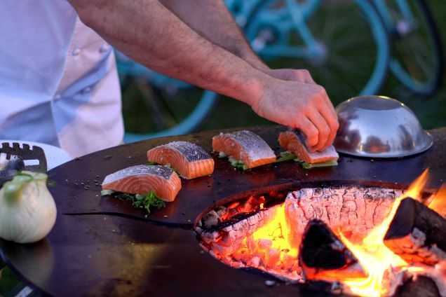 person cooking salmon on grillo chefs anvil tall