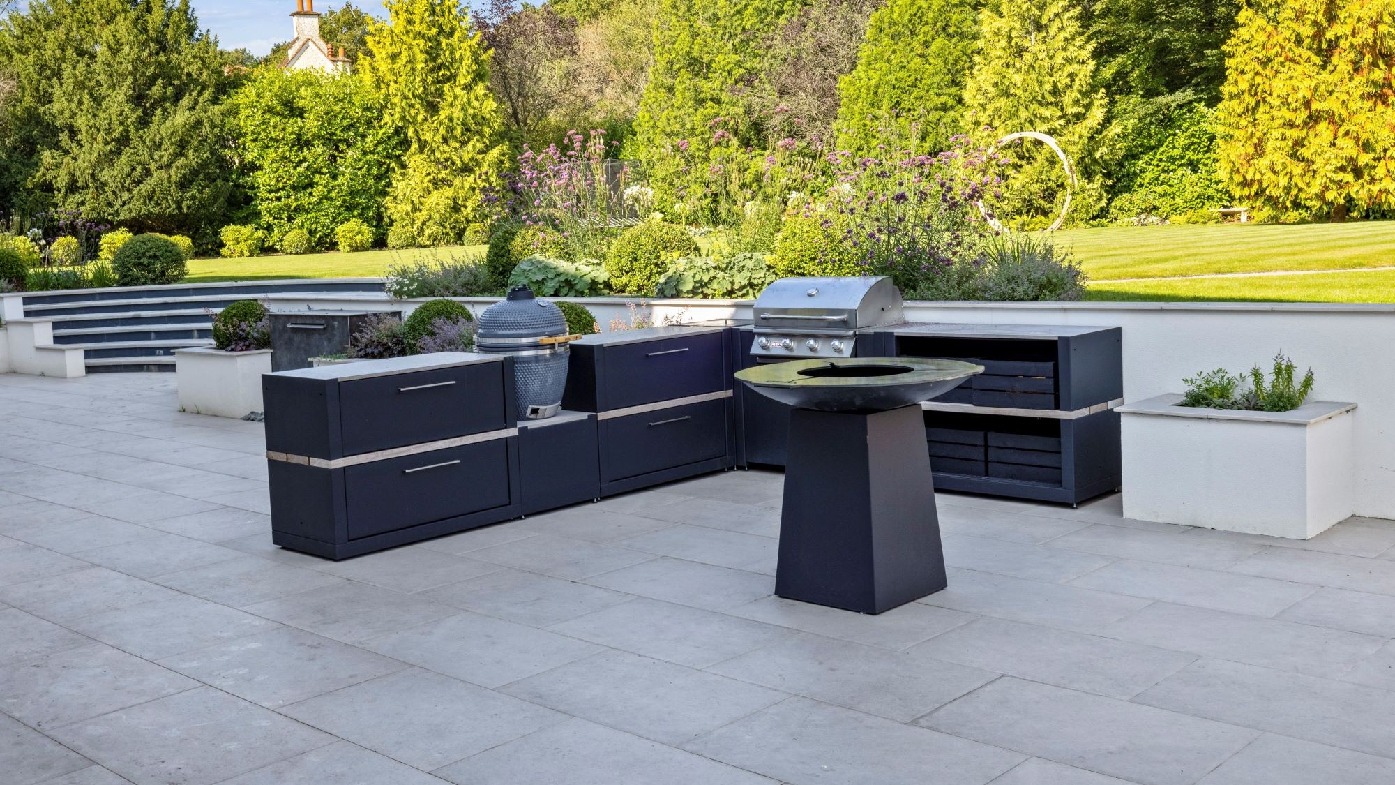 outdoor kitchen on large patio with gas bbq, charcoal bbq and chefs anvil