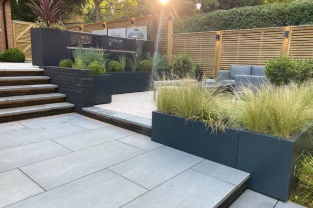 seating area overlooking outdoor kitchen with patterned cabinet backing on raised patio