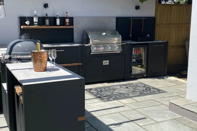 L-shaped outdoor kitchen with bar seating on patio in walled garden on the South Coast