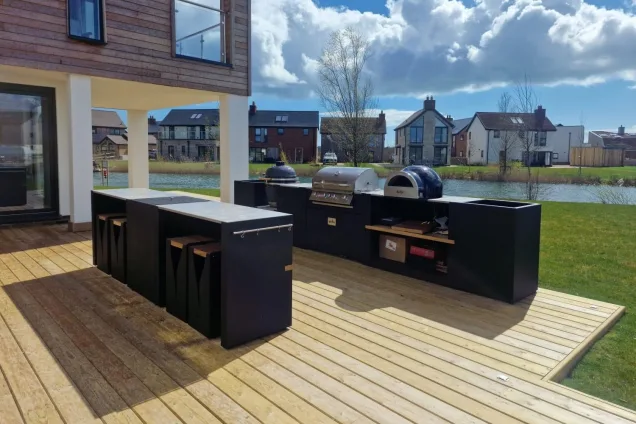 two-row outdoor kitchen with bar seating overlooking lake at Silverlake Holiday Homes in Dorchester, Dorset