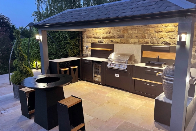 roofed outdoor kitchen with hotplate grill at dusk with lights in Sheffield