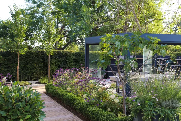 Pavement leading to outdoor kitchen area in landscaped garden in Reigate