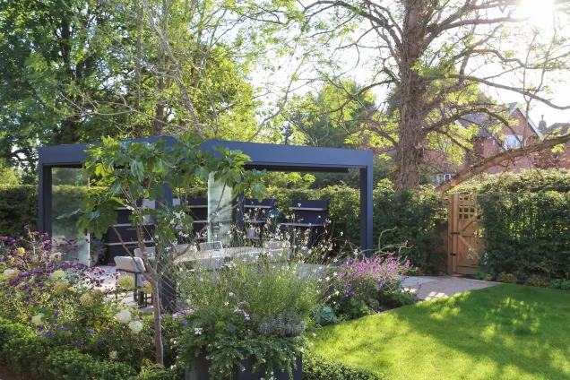 Garden view of outdoor kitchen area on patio with pergola in Reigate