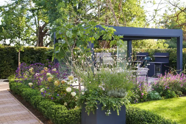 Planter and flowerbed next to outdoor kitchen area in Reigate