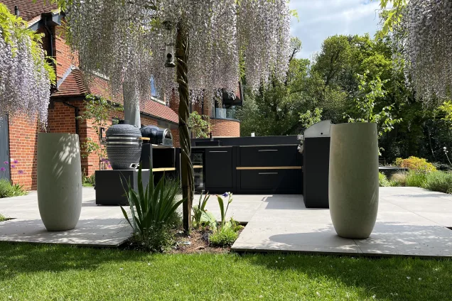 outdoor kitchen with Gusto charcoal BBQ, pizza oven and Bull gas grill on patio with wisteria trees in Reading, Berkshire