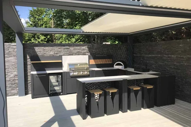 outdoor kitchen under large covering with fridge, bull gas grill station and pizza oven