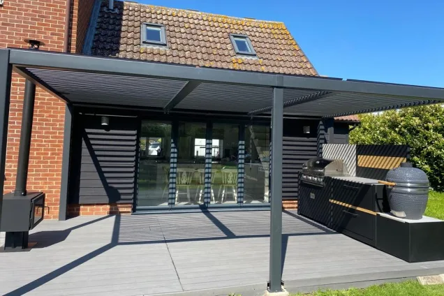 Outdoor kitchen in crowfield under pergola on decking next to house