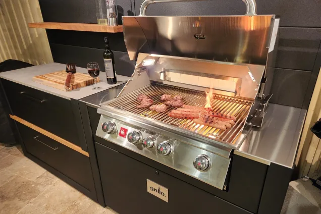 roasting sausages on Bull gas grill in outdoor kitchen in Oatlands, Sydney