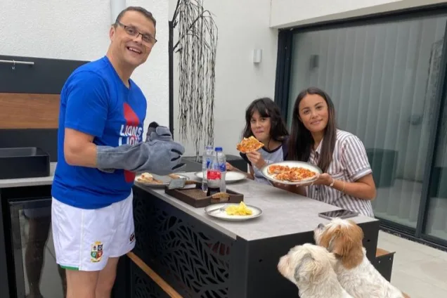 proud owners of outdoor kitchen serving food and eating at bar table with their dogs in New Longton, Preston