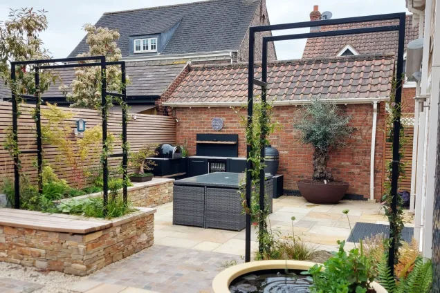 water fountain and planters overlooking outdoor kitchen in courtyard in Mountsorrel, Leicestershire