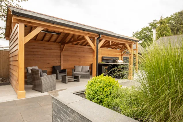 Outdoor kitchen in Cheshire under wooden pergola on patio with plants