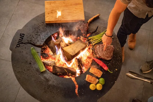 person cooking meat and vegetables on hotplate of chefs anvil