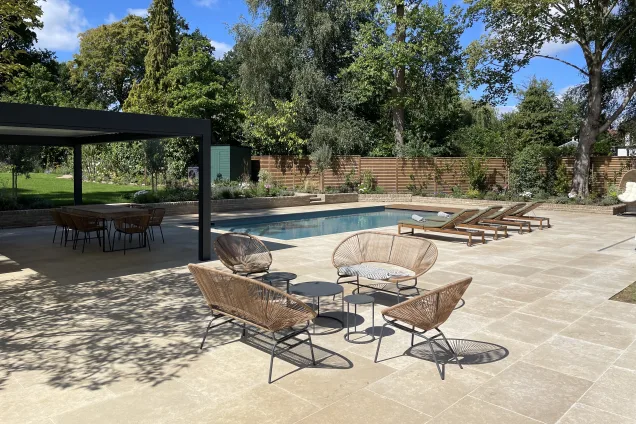 Outdoor kitchen in sussex under pergola next to outdoor pool and seating area