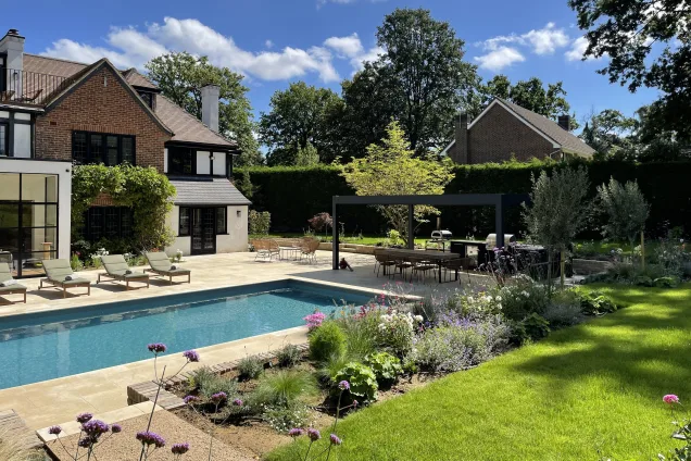 Outdoor kitchen in sussex under pergola next to outdoor pool in garden