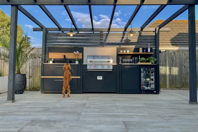 Outdoor kitchen in sussex with bull bbq and storage units with dog