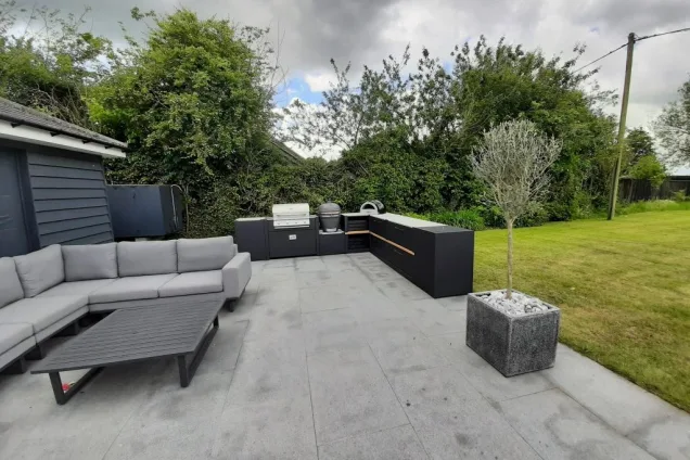 Outdoor kitchen in Sudbury with Charcoal, gas bbqs with storage units and seating on patio with plants