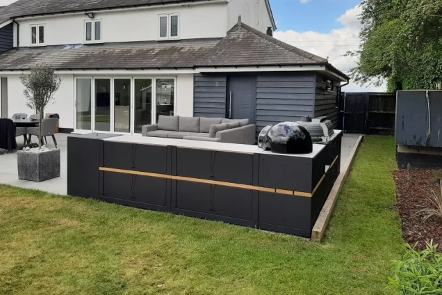 Outdoor kitchen in Sudbury with Charcoal, gas bbqs with storage units and drinks station with house in background
