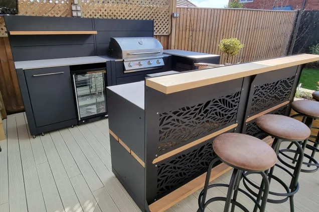 Outdoor kitchen in Kempston with stools at bar cabinets and gas bbq and drinks fridge