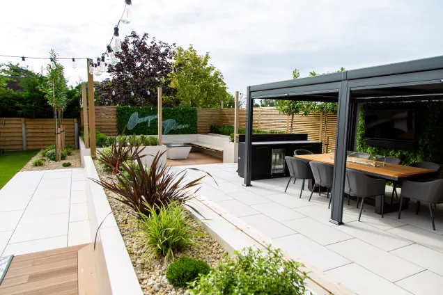 Outdoor kitchen in Leicestershire under pergola in landscaped garden with outdoor bar with fridge and bin