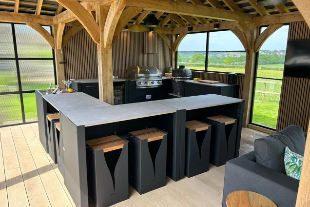 Outdoor kitchen in Hertfordshire with Bar table and stools and seating area and bull gas bbq