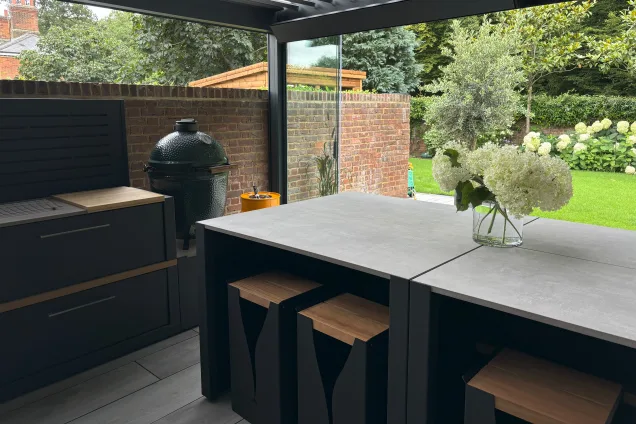 Outdoor kitchen in Hertfordshire with charcoal bbq and island with stools