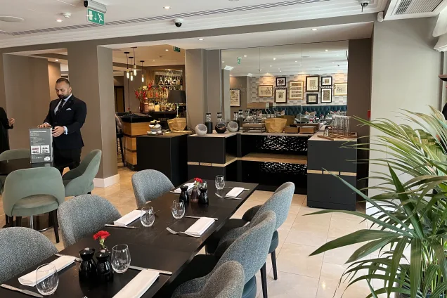 Outdoor kitchen in hotel with storage cabinets with food on the worktops and table set to eat