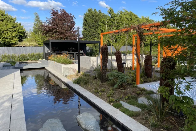 Outdoor kitchen in Bedfordshire with water features and vegetable garden with orange metal features