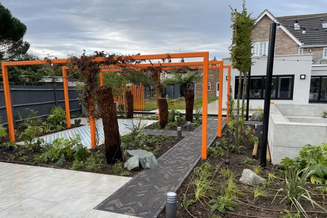 Outdoor kitchen in Bedfordshire with orange metal features and stone paths in garden