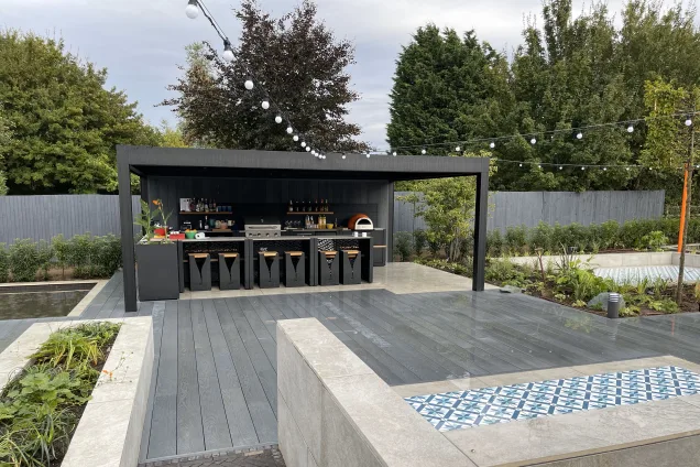 Outdoor kitchen in Bedfordshire on decking with stone and metal features in garden