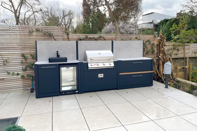 Outdoor kitchen in ealing on white patio with Bull bbq with feature walls and worktop and storage space