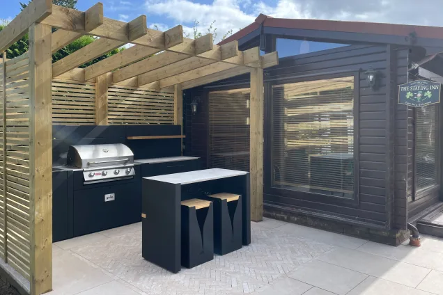 outdoor kitchen with bar seating under pergola in Dunstable
