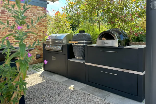 Outdoor kitchen in saffron walden with Gas bbq, charcoal bbq and pizza oven on storage units under canopy