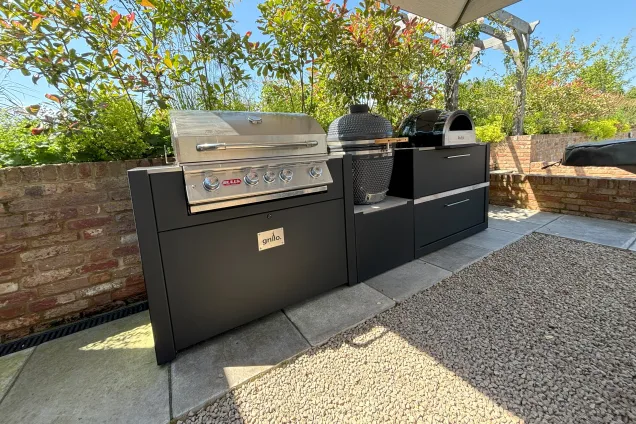Outdoor kitchen in saffron walden under canopy with chefs anvil, gas bbq, charcoal bbq and pizza oven on patio
