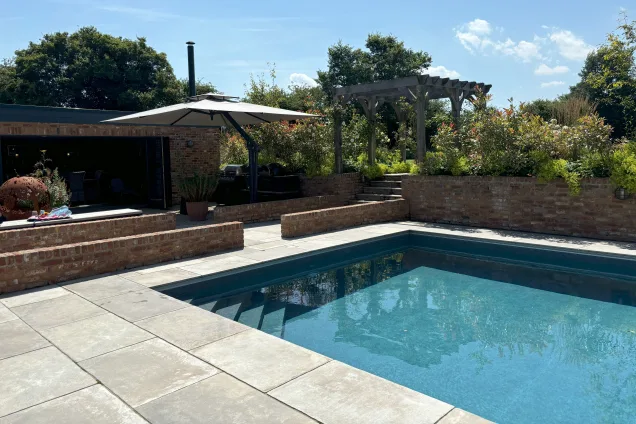 .Outdoor kitchen in saffron walden next to large outdoor swimming pool