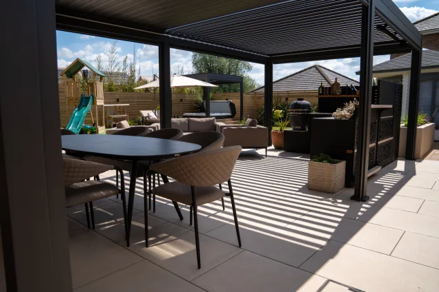 outdoor kitchen on patio with two seating areas overlooking children's play area in garden in Tamworth, Staffordshire
