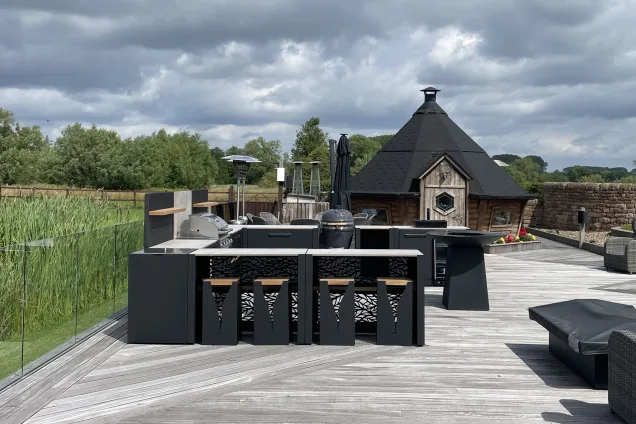 Outdoor kitchen in Stafford on large decking area with chefs anvil and bar table and stools cabinets