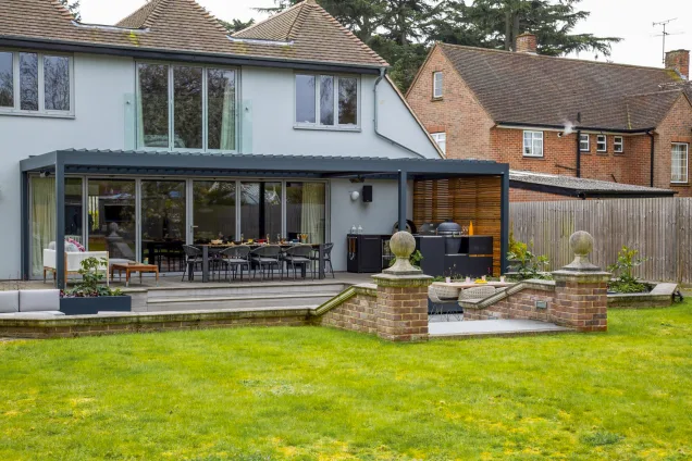 Outdoor kitchen in Colchester with pizza oven, bull bbq and gusto bbq and dining table under pergola in garden