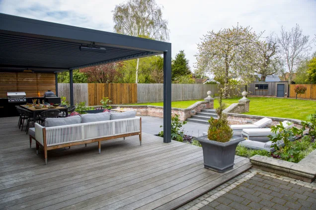 Outdoor kitchen in Colchester with dining table under pergola in garden