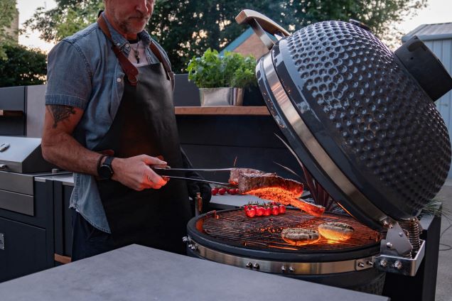 person flipping steak on grillo gusto charcoal bbq