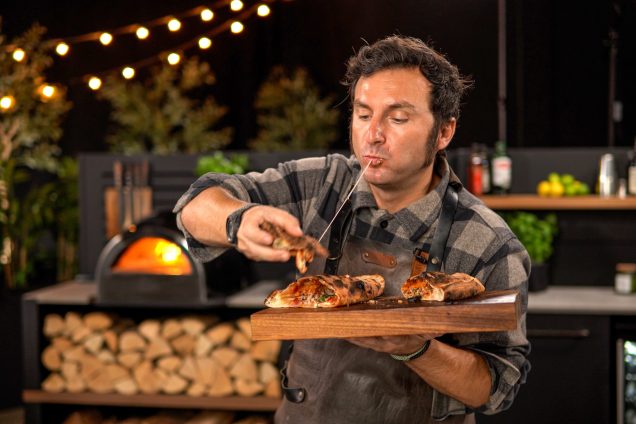 chef eating calzone pizza cooked in grillo outdoor kitchen