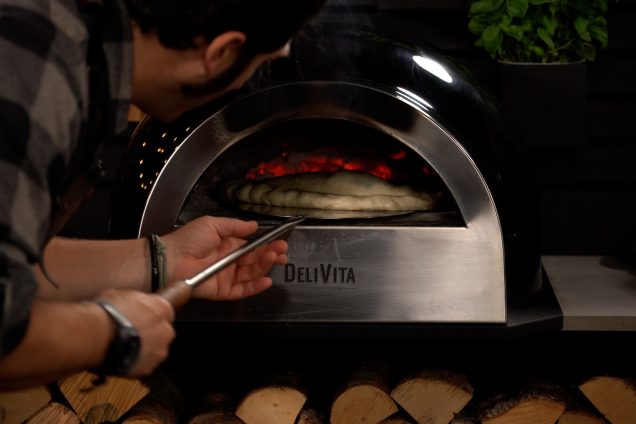 chef turning calzone pizza in wood fired pizza oven