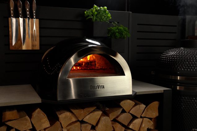 pizza oven on storage cabinet with slatted feature wall in outdoor kitchen